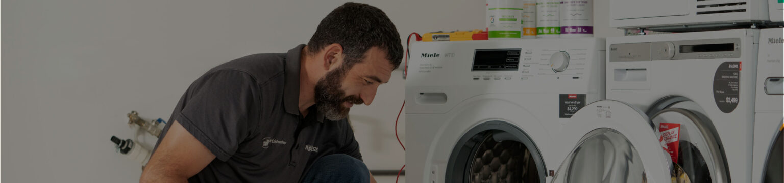 Technician inspecting a washing machine in a clean showroom at Adelaide Appliance Gallery, providing professional Washing machine repairs Adelaide and reliable appliance repairs.
